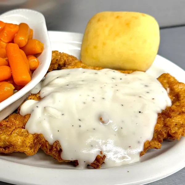 Country fried steak smothered in white pepper gravy with a dinner roll