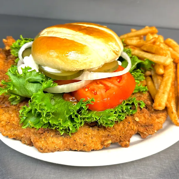 A Hoosier-style breaded pork tenderloin sandwich, bigger than its bun, with steak fries